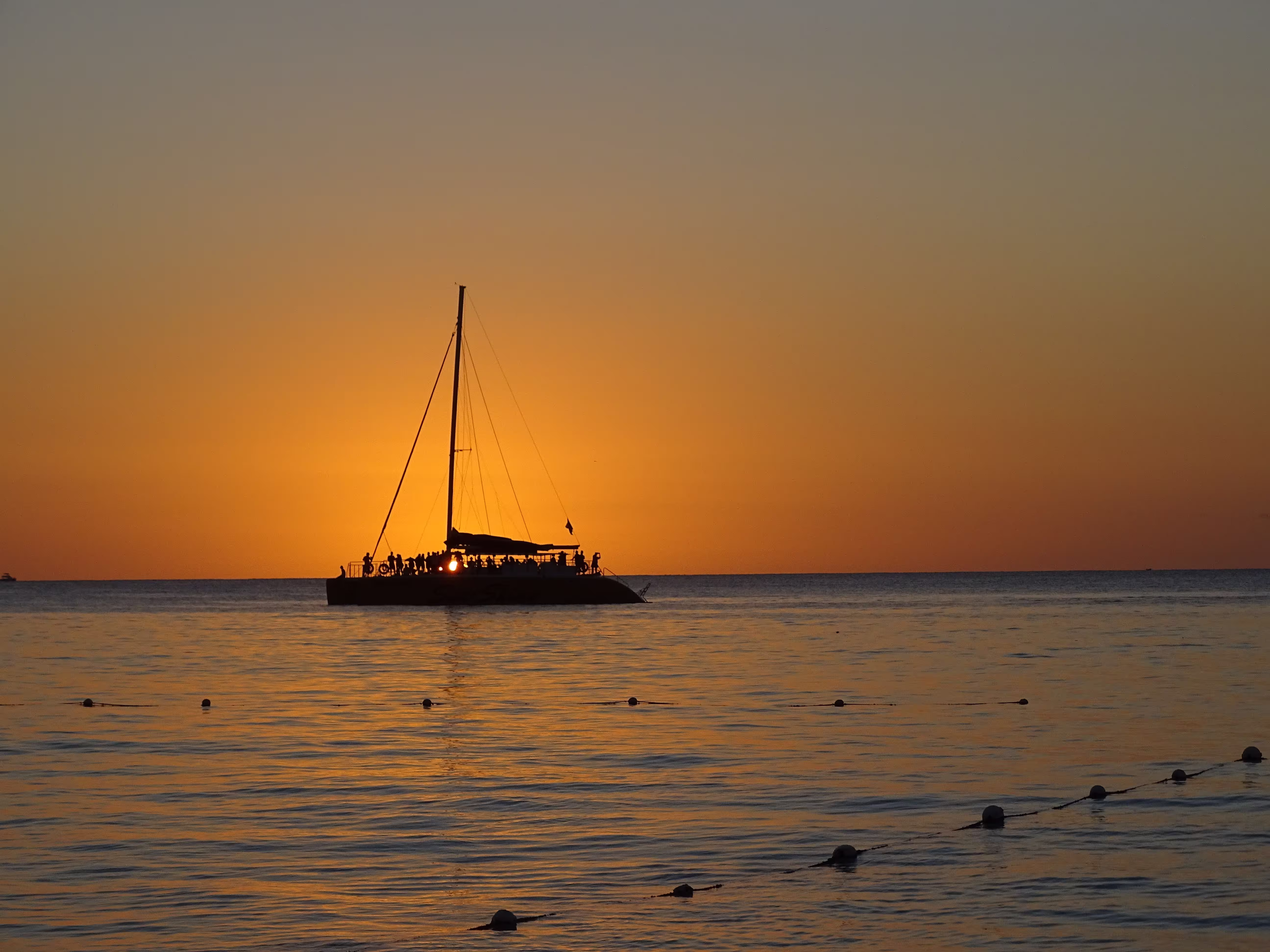 Sailing boat silhouetted against the sunset over the sea